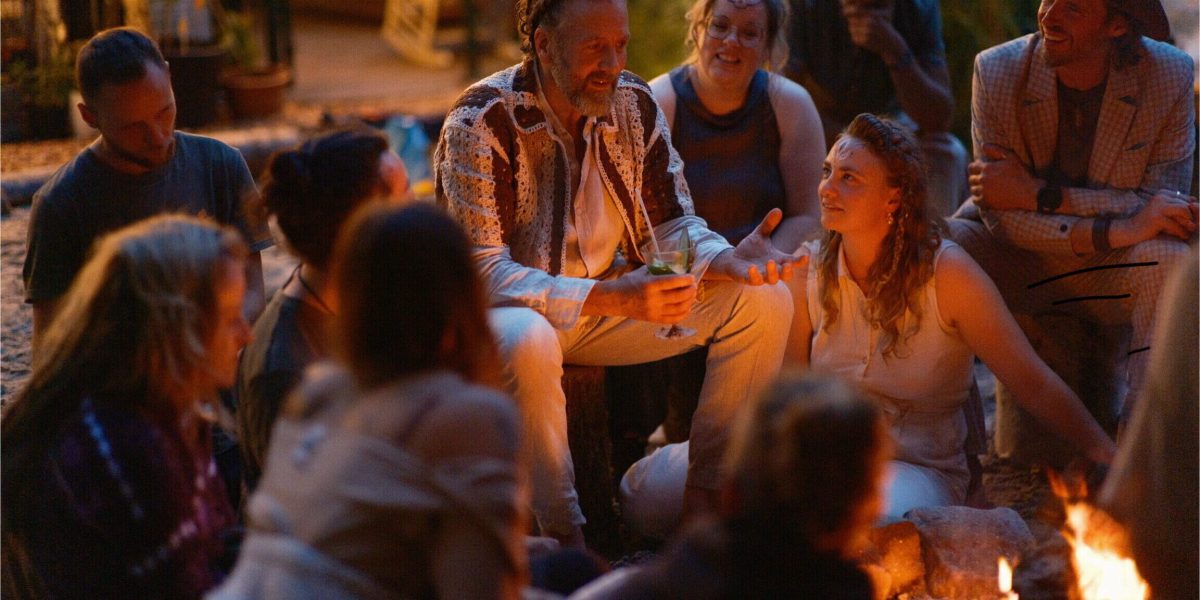 Facilitator sharing a story with participants around a fire at night during the Happie Together festival